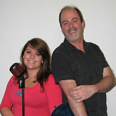 Kayleigh Conrad in a pink top at a vintage microphone beside Rodney Lemish in a gray shirt with an acoustic guitar — LittleRock Express